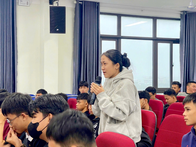 A person holding a microphone in front of a group of peopleDescription automatically generated