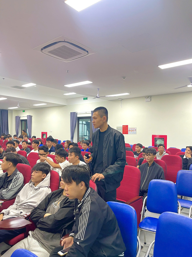 A person standing in a room with a group of peopleDescription automatically generated